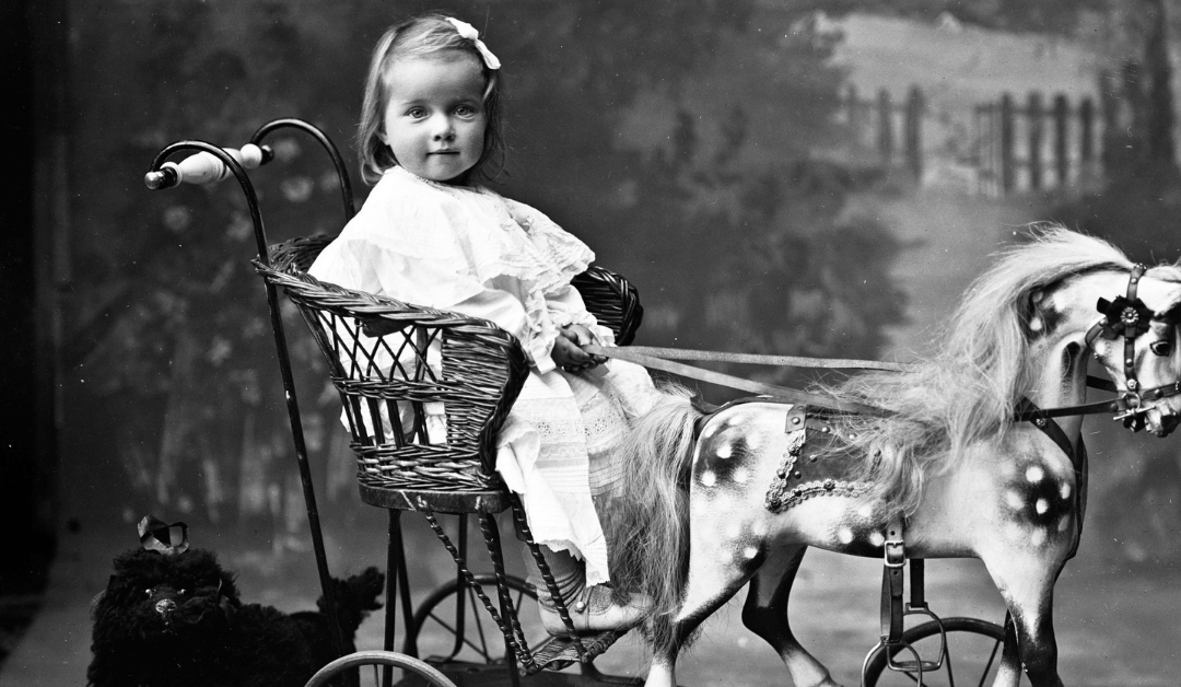 vintage photo of a baby girl sitting in a carriage